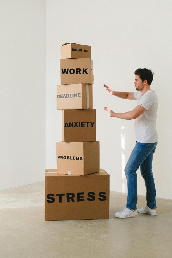 Man with stacked boxes that may fall over labelled with stressful items